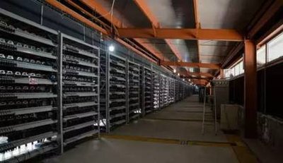 Mining farm featuring rows of mining rigs inside a large, climate-controlled facility.